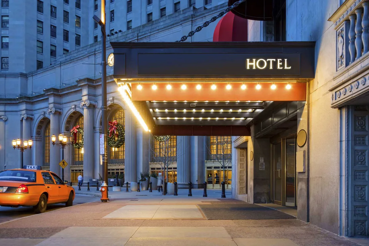 Hotel entrance with a lit marquee at dusk